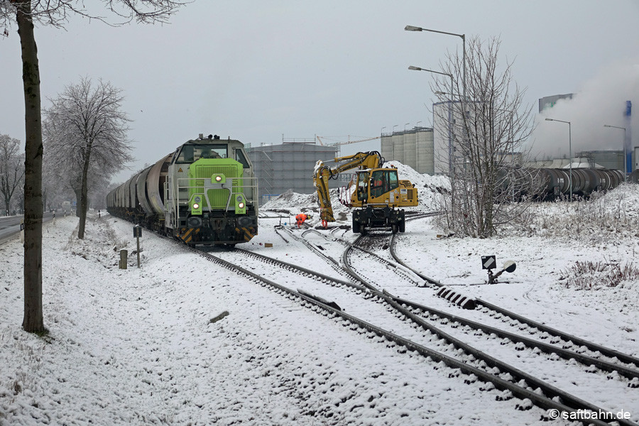 Trotz Winterwetter laufen die Gleiserweiterungsarbeiten in Zörbig weiter. Nach Abstellung der Wagengruppe auf dem Streckengleis, muss die Lok die Räumung des Anschlussgleises durch einen Zweiwege-Bagger kurz abwarten.